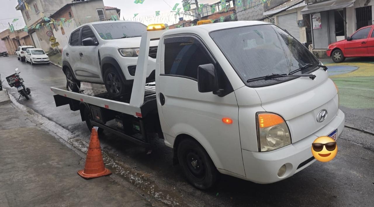 Guincho plataforma da Luizera carregando um hatch branco em rua de São Paulo