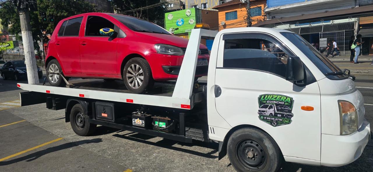 Guincho da Luizera transportando um Volkswagen Fox vermelho em avenida movimentada